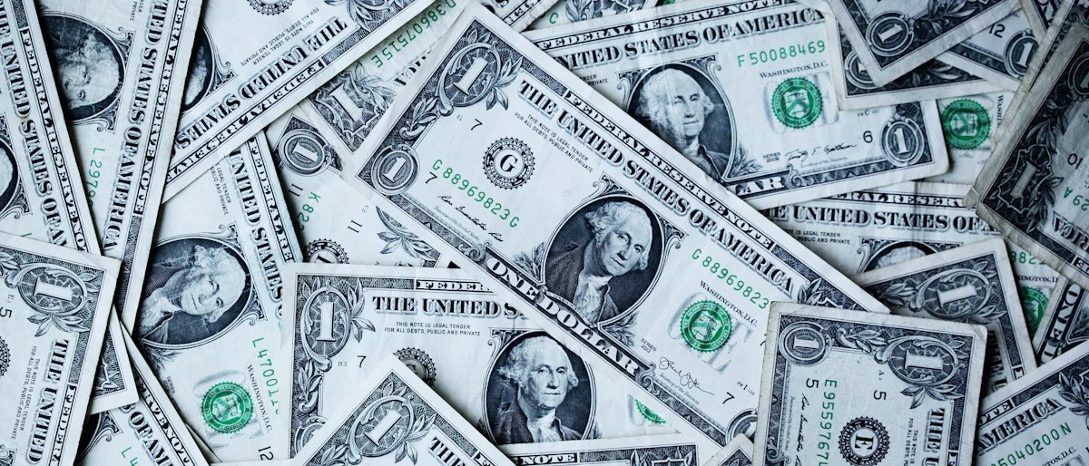 Üst üste dağınık hâlde duran çok sayıda bir dolarlık banknotun yakın çekimi